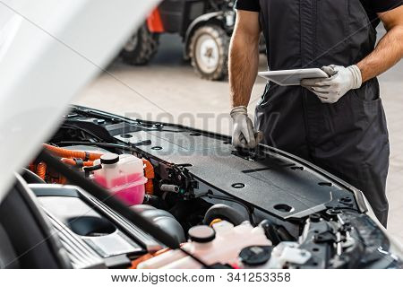 Partial View Of Mechanic Holding Digital Tablet Near Car Engine Compartment