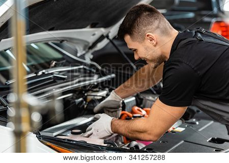 Selective Focus Of Smiling Mechanic Inspecting Car Engine Compartment
