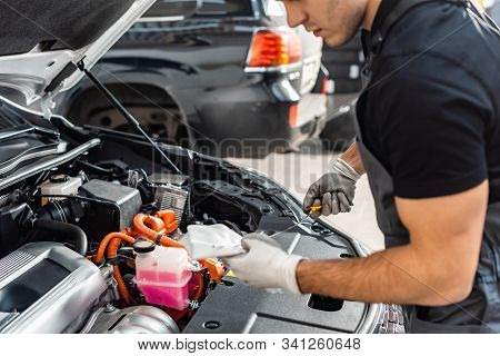 Partial View Of Mechanic Wiping Oil Dipstick With Rag Near Car Engine Compartment