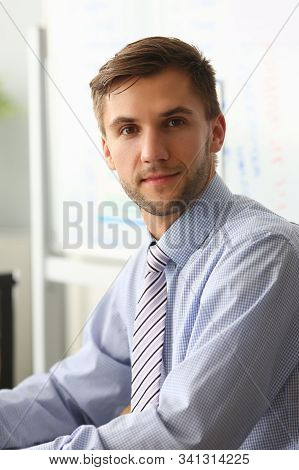 Portrait Of Handsome Young Company Employee Sitting In Private Office. Male Wearing Presentable Suit