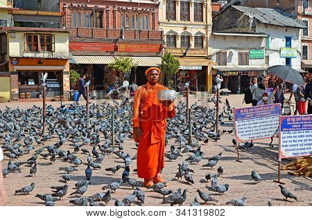 Kathmandu, Nepal - March 14, 2018: A Buddhish Monk In Bright Orange Clothes Standing At The Buddha S