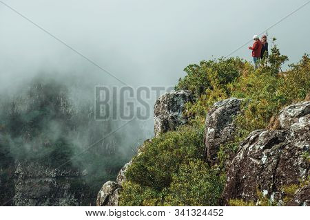 Cambara Do Sul, Brazil - July 18, 2019. People On Steep Rocky Cliff At Fortaleza Canyon With Mist Co