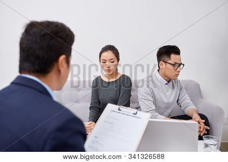 Young Angry Couple Of Cheated Investors Holding Papers Arguing With Male Real Estate Agent, Defraude