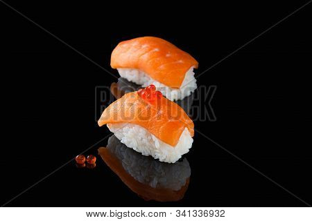 Sushi Nigiri With Salmon - Syake With Red Caviar On A Black Background With Reflection. A Dish Of Ri