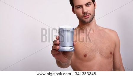 Naked Cool Strong Man Holds In His Hand Gray Deodorant And Looks At Frame Seriously. Anti Smell Armp