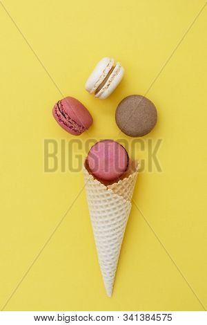 Macarons Cakes. Stil Life Photo Of Waffle Cone With Macaroons On Yellow Background. Flat Lay, Desser