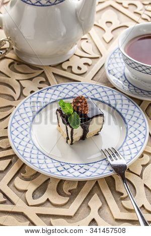Vanilla Souffle With Dark Chocolate Glaze And Cup Of Tea On Orientabl Wooden Table