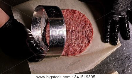 Cook Makes Meat Medallions For Burgers. Chef In Black Food Gloves Makes Cutlet. Cutlets Are Leveled 