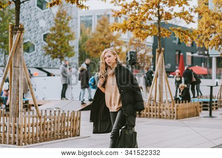 Street Fashion Portrait Of Young Beautiful Woman Wearing Beige Roll Neck Pullover And Black Padded C