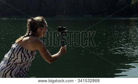 Woman Shooting On Handheld Film Gimbal Stabilization For Smartphone. Girl Stand On Pier Make Selfie.