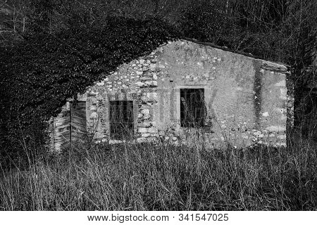 Farmhouse Covered With Vegetation Abandoned Along A Path In Arsiero, In The Province Of Vicenza In T