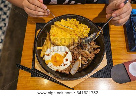 Human Eating Sizzling Beef Sisig Rice On Iron Platter