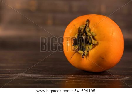 Persimmon Ripe Orange On A Wooden Brown Table