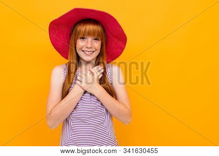 Young Girl In Purpe T-shirt With Red Hair And Pink Hat Smiles And Hopes For Something Isolated On Ye