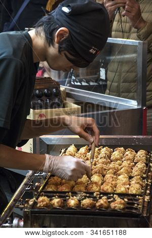 Osaka, Japan- 27 Nov, 2019: Vendor Making Takoyaki On A Takoyaki Pan In Osaka, Japan. Takoyaki Is Fa