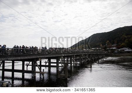 Kyoto, Japan-26 Nov, 2019: Togetsu-kyo Bridge Over Katsuragawa River With Colourful Forest Mountain 