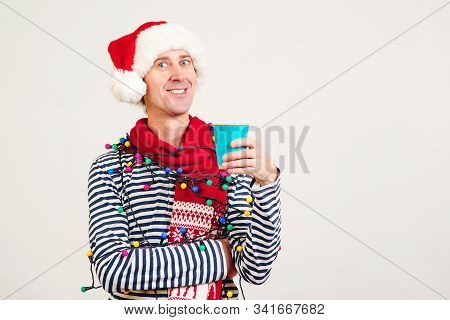 Coffee Break For Santa Helper. Copy Space For Text. Smiling Man In Santa Claus Hat Holding A Paper C