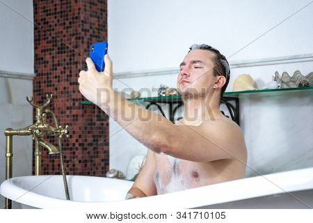 Young Handsome Naked Caucasian Man  Blogger For Social Networks In Bathtub Makes Selfie On Mobile Ph