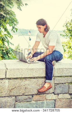 Young Man With Long Hair Traveling, Working In New York City, Wearing White Shirt, Blue Jeans, Brown