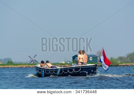 Undefined Two Couples Man And Woman Sunbathing In Swimpacks On Boat Floating On River In Netherland 