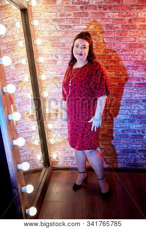 Fat Plump Charming Cute Woman With Black Hair In Red Beautiful Dress In The Room With Mirrow And Red