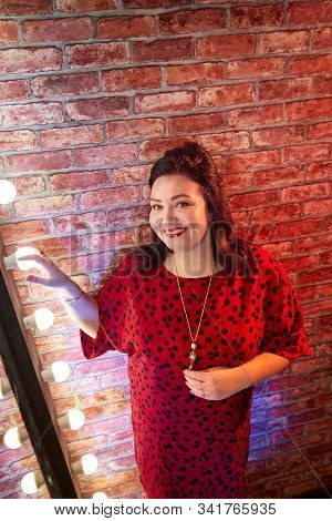 Fat Plump Charming Cute Woman With Black Hair In Red Beautiful Dress In The Room With Mirrow And Red
