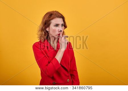 Attractive Caucasian Young Woman Pointing Fingers On Nose, Loooking Aside Wearing Fashion Red Jacket