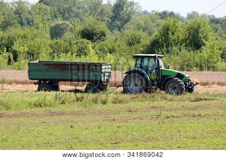 Green And Black Farm Tractor With Connected Rusted Vintage Old Tractor Trailer Left In Local Field S