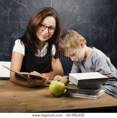 Little Cute Boy In Glasses With Young Real Teacher, Classroom Studying At Blackboard School Kido