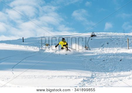 Sportsman In Helmet Holding Ski Sticks While Skiing On Slope Outside