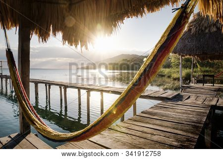 Hammock At Dock During Sunset With Sun Rays Backlight At Lake Itza, El Remate, Peten, Guatemala