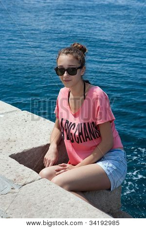 Adolescente, assis au bord de la mer