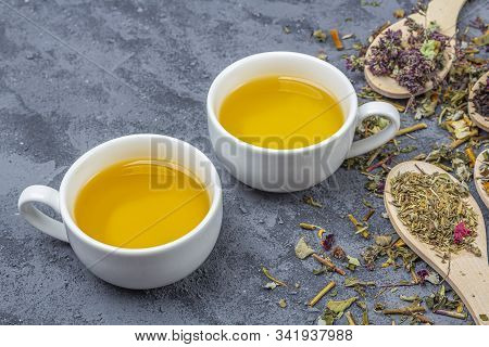 Assortment Of Different Grade Dry Tealeaf In Wooden Spoons And Two Cup Of Green Tea. Organic Herbal,