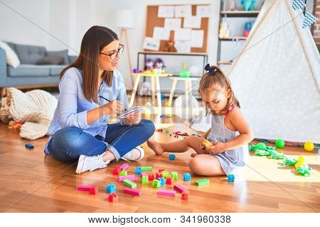 Young therapist woman speaking and treating child, counselor and behaviour correction at pedagogue payroom taking notes on clipboard