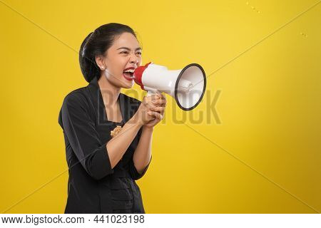 Asian Woman Wearing Kebaya Shouts While Holding Megaphone On Isolated Background