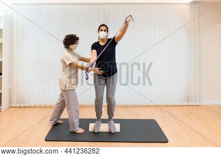 A Pregnant Woman Standing On A Proprioceptive Trunk Or Wooden Roller With An Elastic Band With Physi