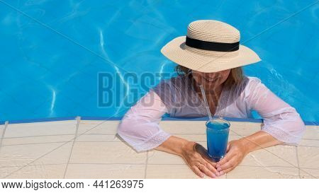Senior Woman Relaxing In The Hotel Swimming Pool. People Are Enjoying Their Summer Vacation. All Inc