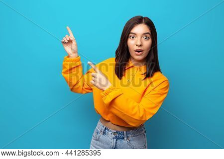 Beautiful Multiethnicity Woman In Orange Trendy Shirt Happily Surprised Expression Pointing With Fin