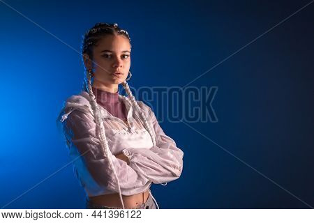 Urban Session. Young Caucasian Woman With Long White Braids On A Blue Plain Background, Rap Or Trap 