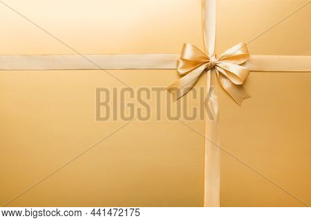 Top View Of Gold Ribbon Rolled And Yellowbow Isolated On Colored Background. Flat Lay With Copy Spac