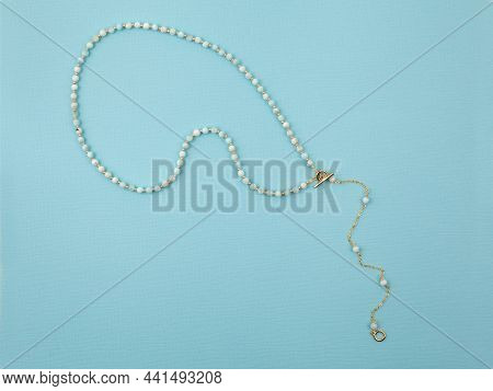 Women`s Necklace Of White Gem Stones On Bright Turquoise Textured Background. 
Top View