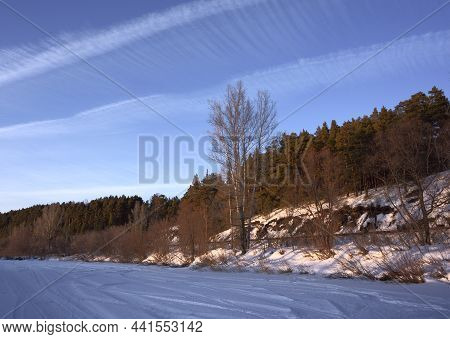 Ripples Of White Clouds In The Blue Sky. The Frozen Bed Of The River Berd Is Covered With Snow. Pine