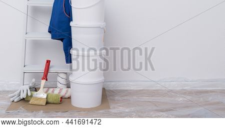 On A White Background, Building Materials, Paint Buckets, Rollers, A Stepladder And Protective Cloth