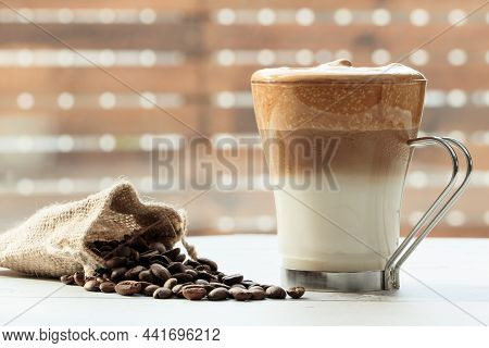 Cup Of Dalgona Coffee On Wooden Table With Bag Of Natural Coffee Beans