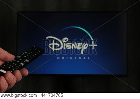 Nikolaev, Ukraine - November 20, 2021. Man With Tv Remote Control In Hand And Disney Logo Background