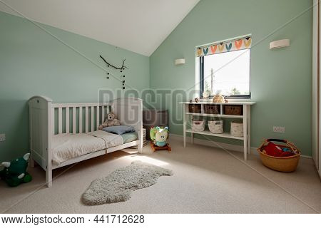 Dry Drayton, England - August 2 2019: Childs Bedroom Space With Cot, Soft Cuddly Toys And Shelved Ta