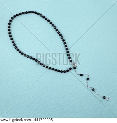 Women`s Necklace Of Black Gem Stones On Bright Turquoise Textured Background. Top View
