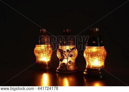 Beautiful Glowing Grave Lights On Table In Darkness. Symbol Of Remembrance