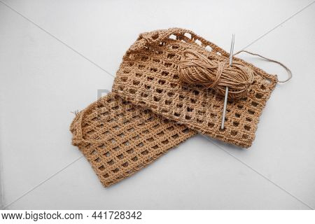 The Product Is In The Process Of Being Created, A Skein Of Mustard Yarn And A Hook On A White Backgr