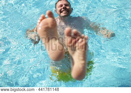 Portrait Of Man Diving Into Water In Swimming Pool With Feet Up. Laughing Cheerful Middle Aged Male 